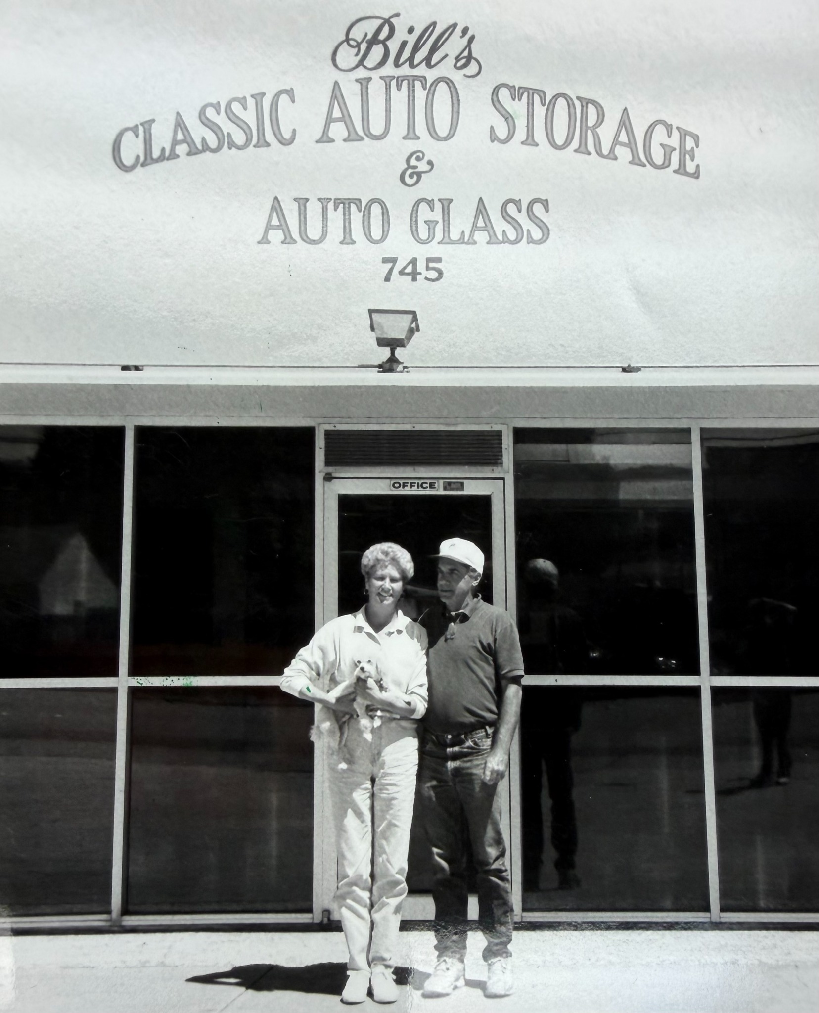 Bill and Rosie standing in front of Bill's Classic Auto Storage and Auto Glass at 745