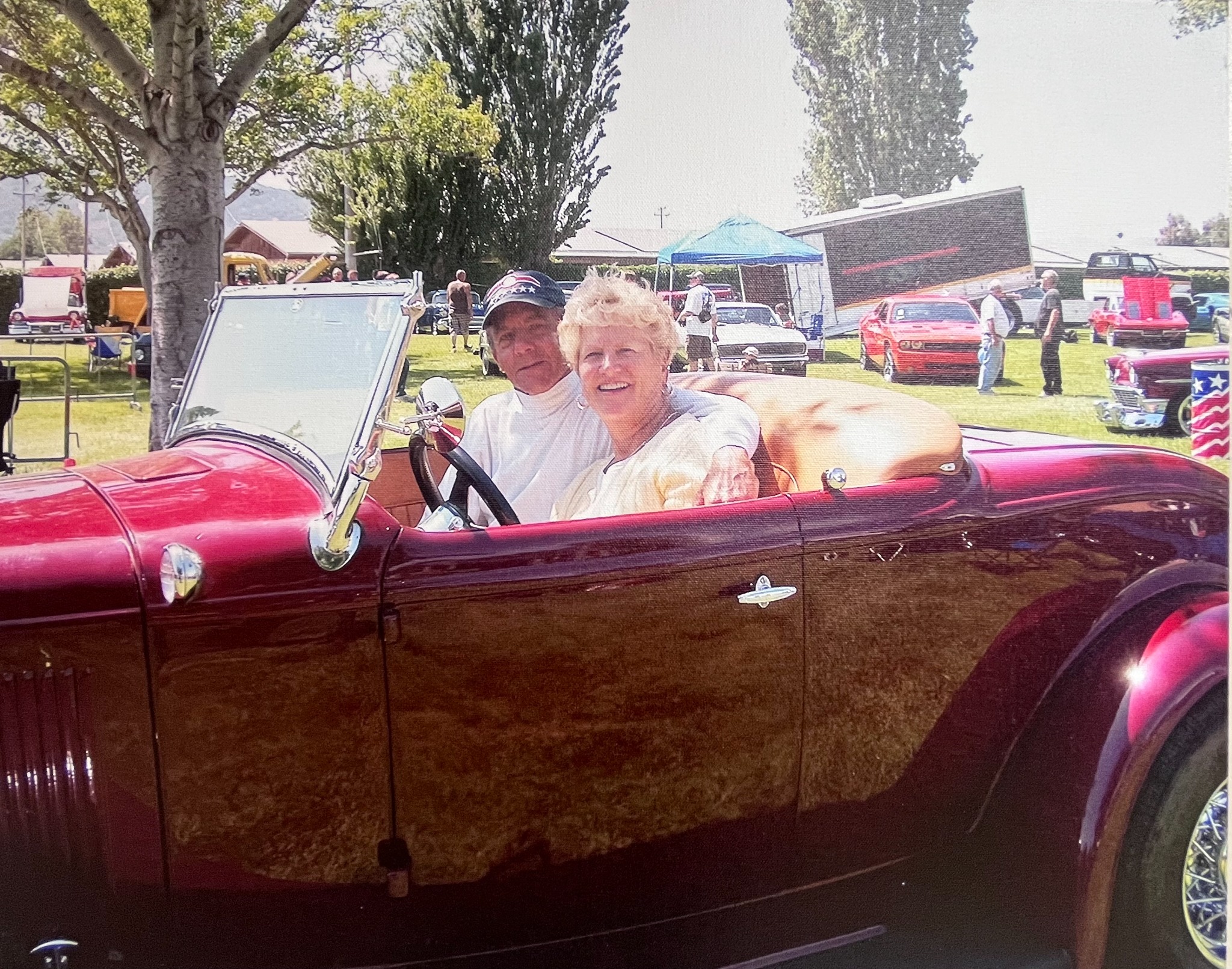 Bill and Rosie in a vintage Ford hot rod at a car show