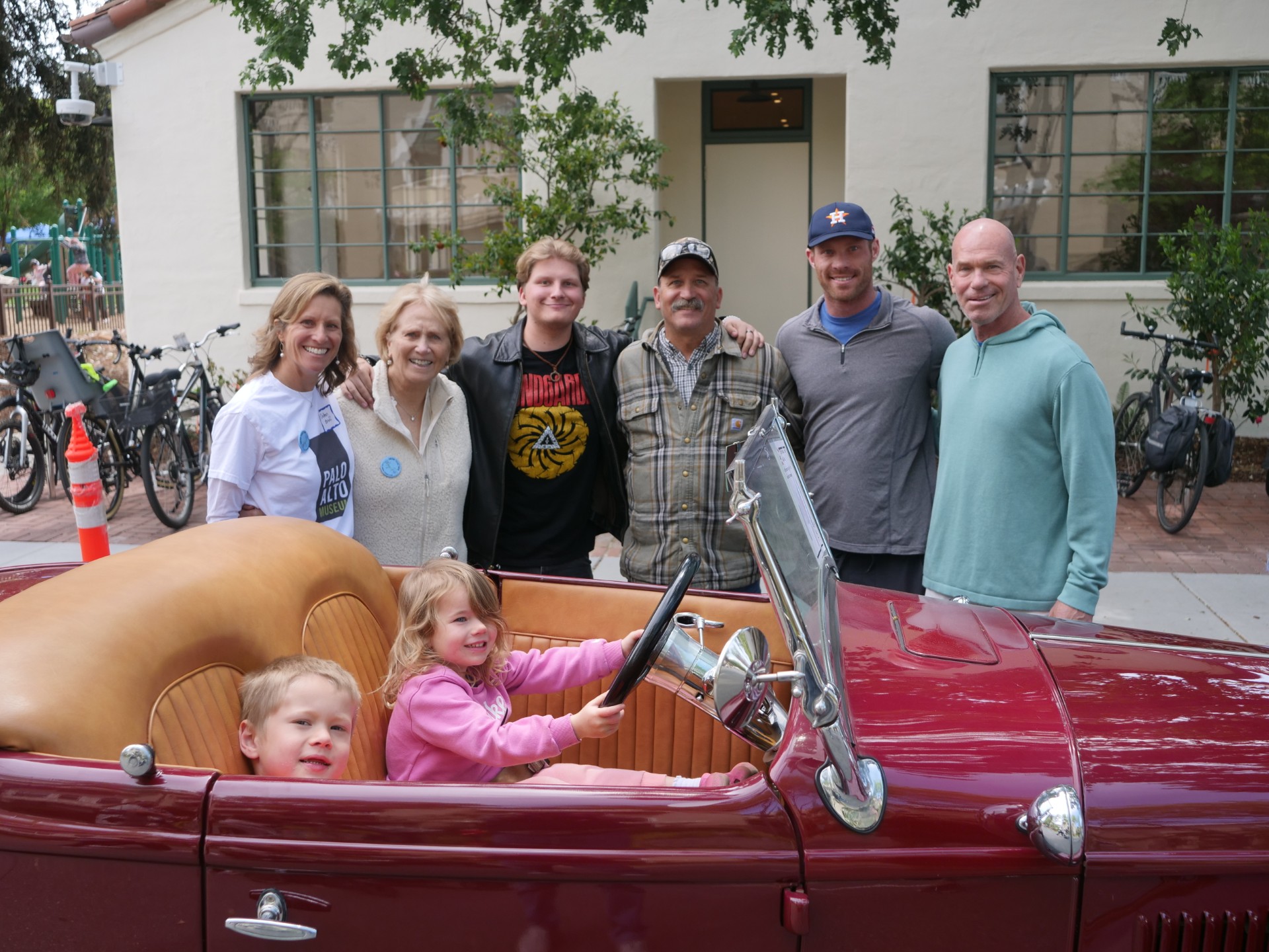 Family gathered around a vintage Ford hot rod